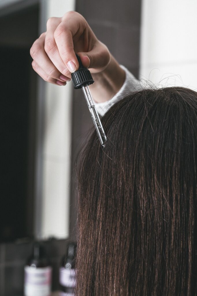 Woman putting oil on hair.
